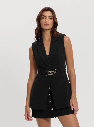 A woman wearing a black sleeveless belted longline vest with button details and a belt.