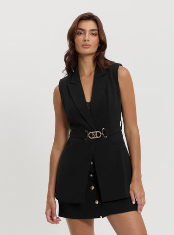 A woman wearing a black sleeveless belted longline vest with button details and a belt.